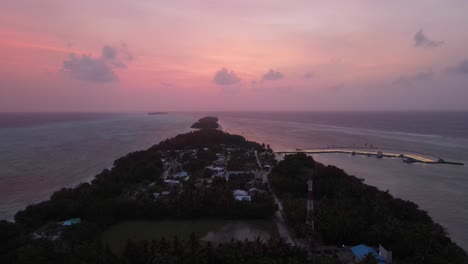 disparo mágico de drones después del atardecer en maldivas volando sobre una isla con nubes en la distancia y cielo rosa