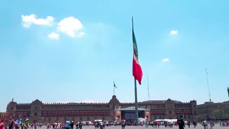 still image of mexican flagpole, national palace visible in the background, cdmx