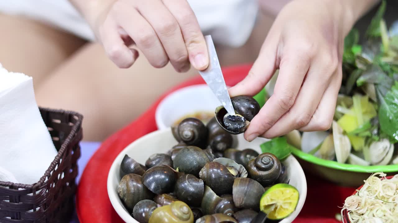 손은 허브와 라임 조각으로 조개를 준비하고 있습니다.