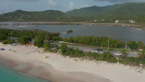 Aerial-side-view-green-open-roof-4wd-drive-on-Antigua-and-Bermuda-coast-surrounded-by-ocean-and-green-nature-in-Caribbean