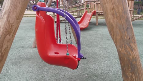 red plastic swing set in a playground