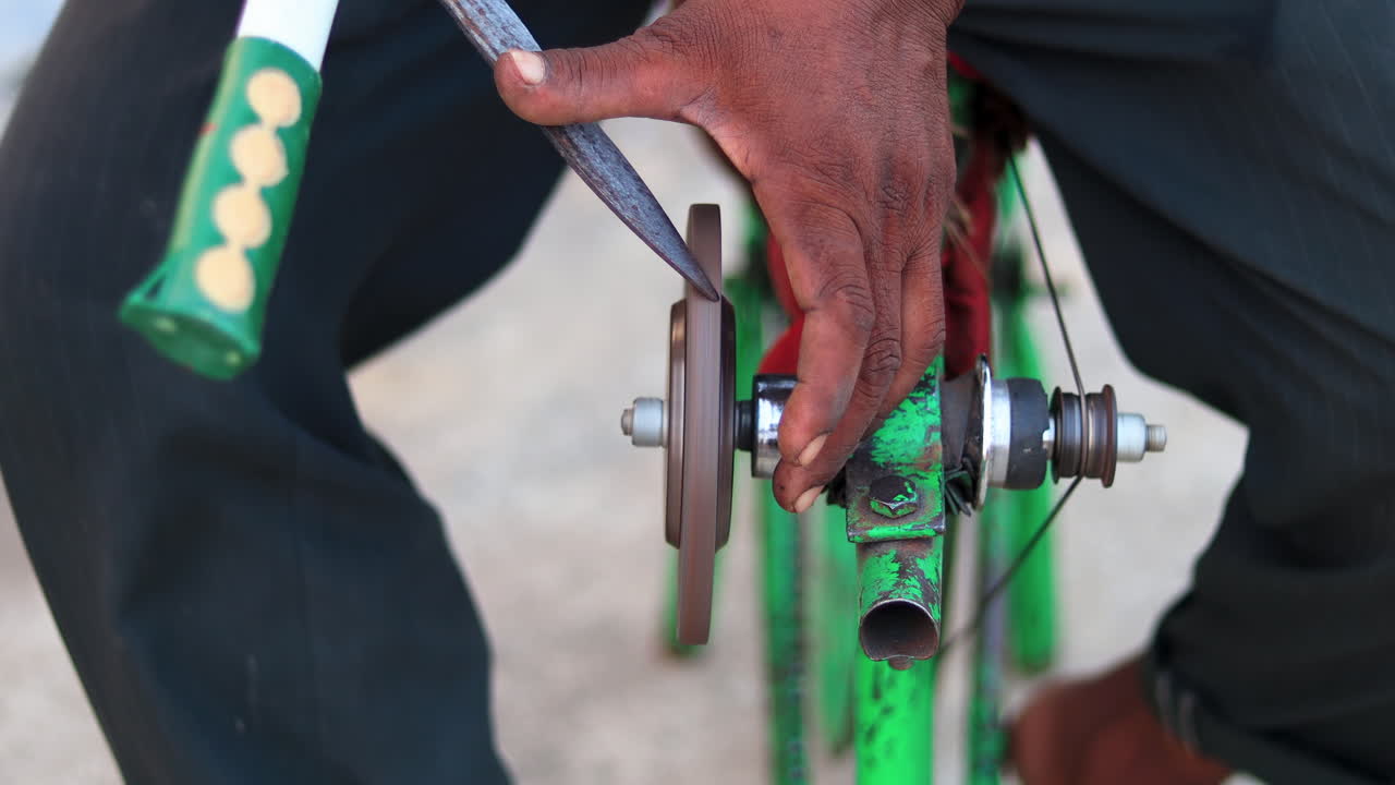 Top view of a man sharpening gardening scissors on a makeshift mobile sharpening machine on a manual bicycle frame