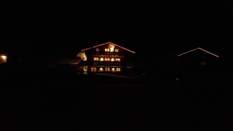 Drohne-Fliegt-Nachts-Langsam-Mit-Brennenden-Lampen-Und-Weihnachtsbeleuchtung-Auf-Ein-Wunderschönes-Chalet-Zu