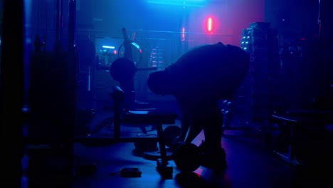 man lifting weights in a gym at night