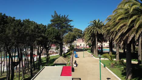 Aerial:Parque-Ross,-historic-casino-cultural-center-1904-near-shot-park-contains-native-Canary-date-palms-over-a-hundred-years-old-and-many-green-spaces-pichilemu-puntilla-punta-de-lobos-chile