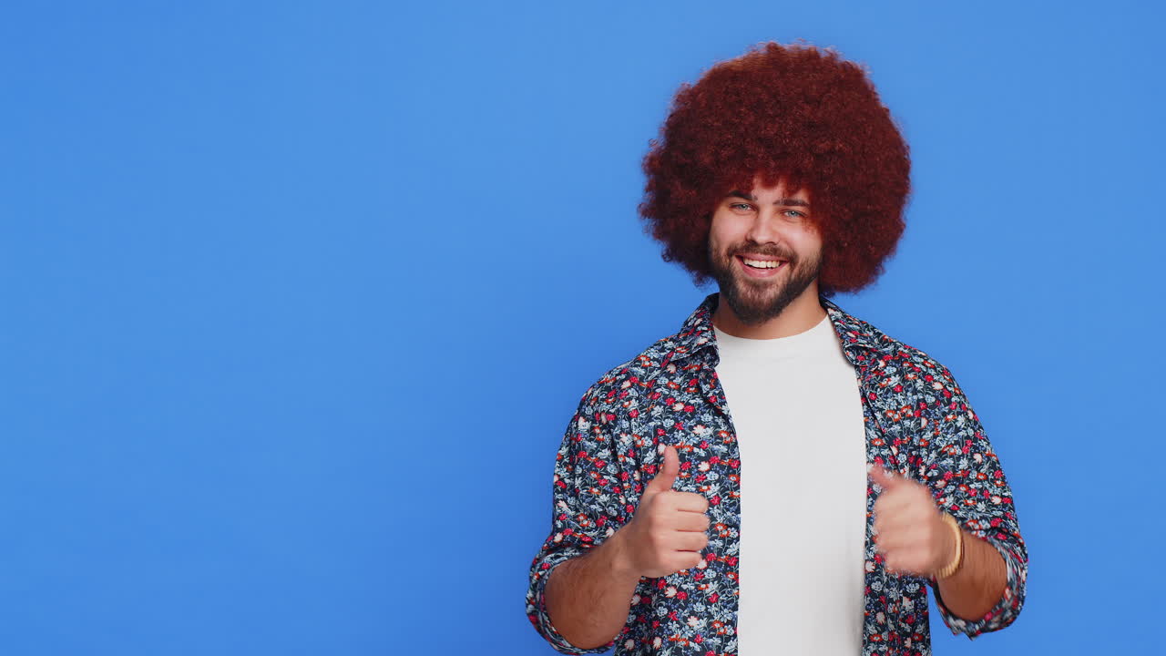 joven mostrando los pulgares hacia arriba y señalando a la izquierda en el espacio en blanco lugar para su logotipo de publicidad
