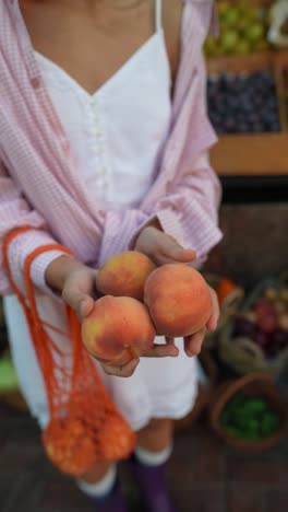 woman buying peaches at a farmers market