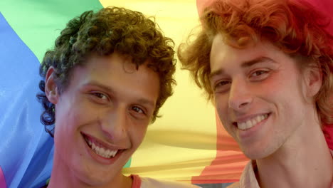 portrait of happy diverse gay male couple holding rainbow lgbt flag and smiling, slow motion