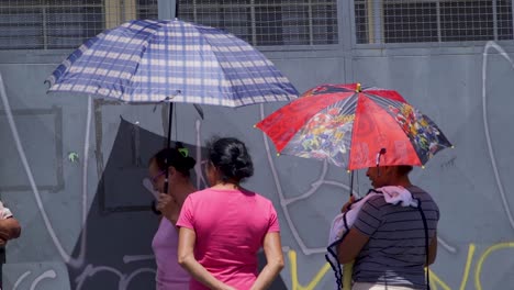 two women using umbrellas for sun protection on a street