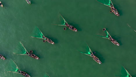 an aerial shot over hundreds of traditional conical basket boats and trawler fishing boats in ocean vietnam asia