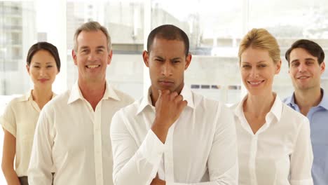 Businessman-looking-at-camera-with-staff-behind-him