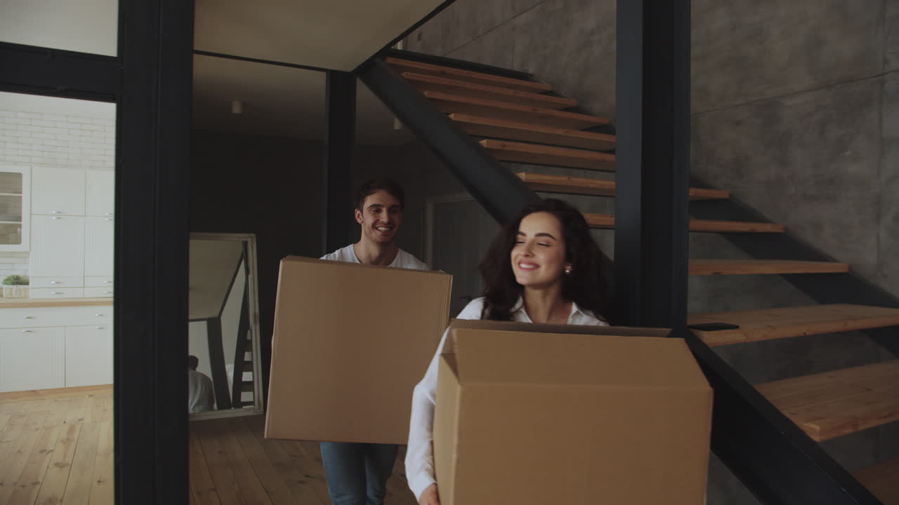 Happy couple with boxes moving in to luxury house together
