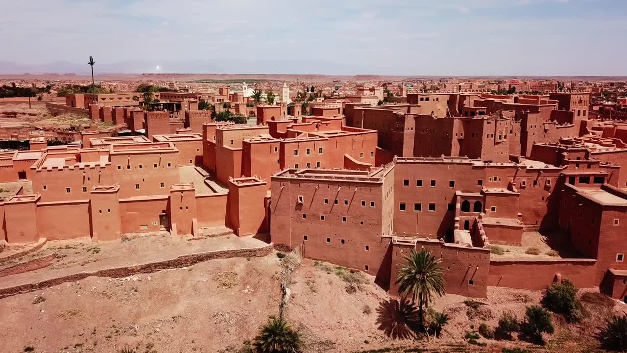 Veduta con drone di una kasbah tradizionale marocchina nella regione di Ouarzazate, famosa per le produzioni cinematografiche. Architettura densa in adobe in un contesto desertico, ideale per immagini di viaggio, cinema e patrimonio culturale.