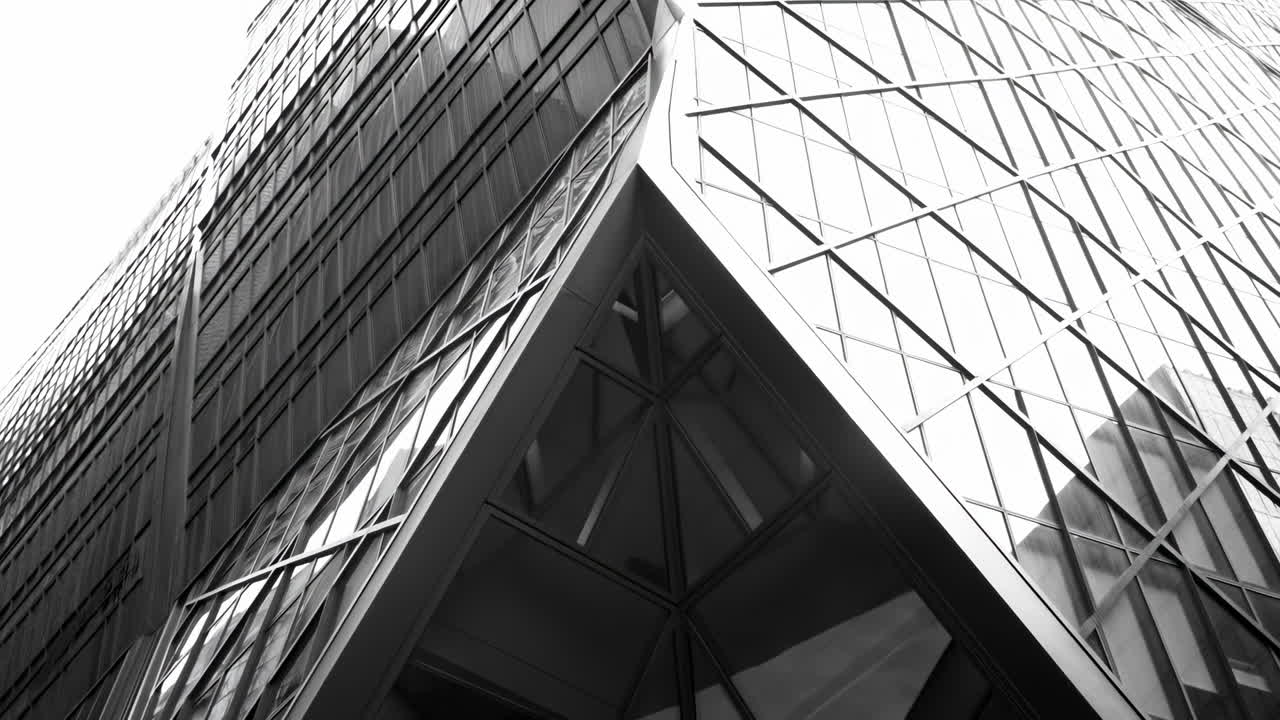 Panoramica verso l'alto di un moderno grattacielo in vetro in monocromatico