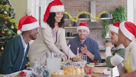 grupo feliz de diversos amigos en sombreros de santa celebrando la comida en tiempo de navidad