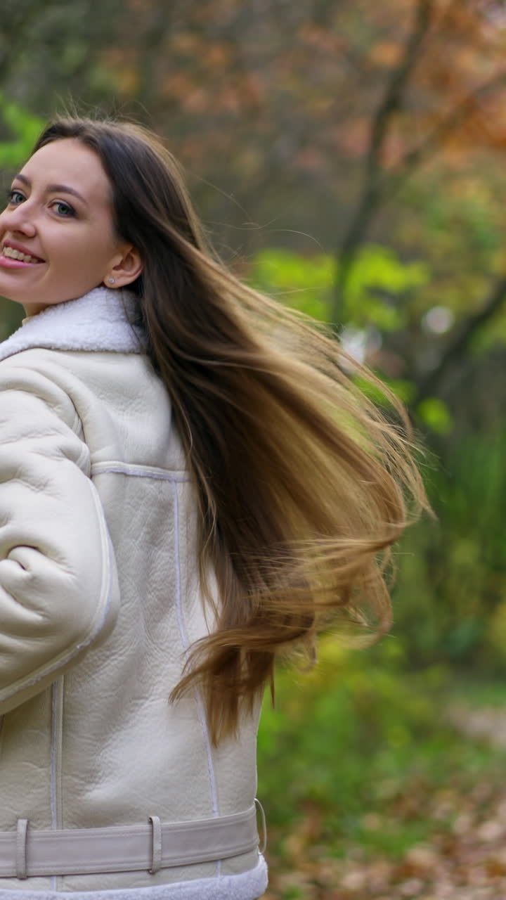 Following the brunette long-haired lady walking by the park. Woman turns around, walks backwards and then turns again, camera view on her feet.