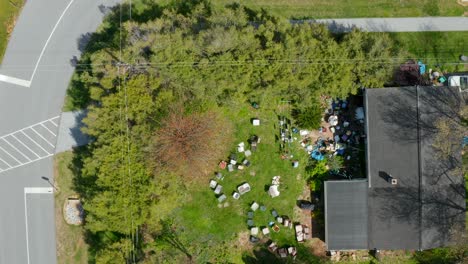 Descending-aerial-on-backyard-filled-with-junk,-trash-and-debris