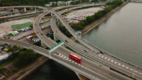 drone orbit shot of cars driving on highway over waterway bridge, hongkong