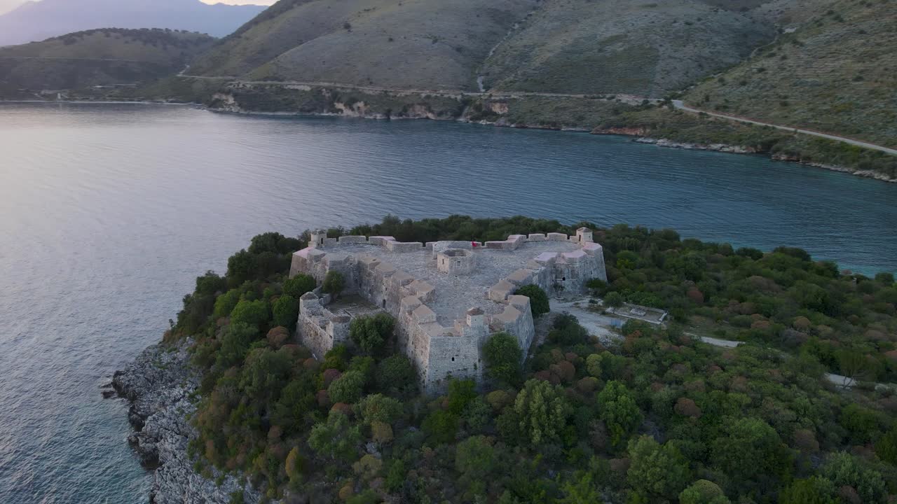 알바니아의 포르토 팔레르모 성 상공에서 중간 거리에서 환상적인 원형 공중 촬영 및 멋진 풍경과 강렬한 푸른 바다를 시각화