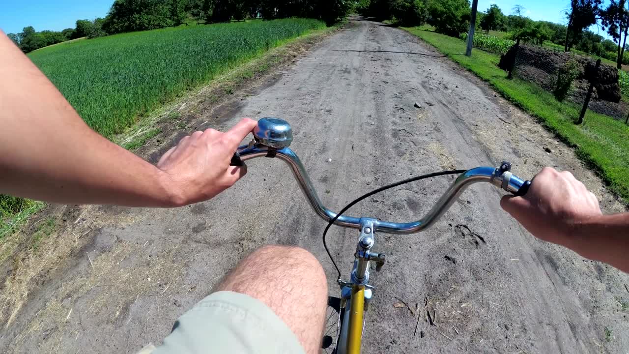 un hombre está montando una bicicleta en una carretera rural en el pueblo. vista desde el cofre en la rueda