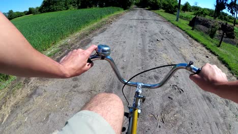 man is riding a bicycle on a rural road in the village. view from the chest on the wheel