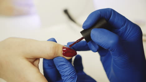 master of nails paints nails with red lacquer in the salon. relaxing day at beauty salon. close-up