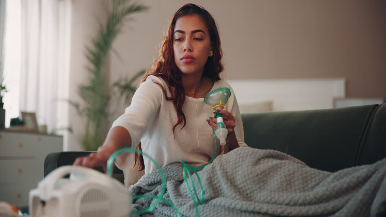 mujer sentada en un sofá usando un nebulizador para el tratamiento respiratorio