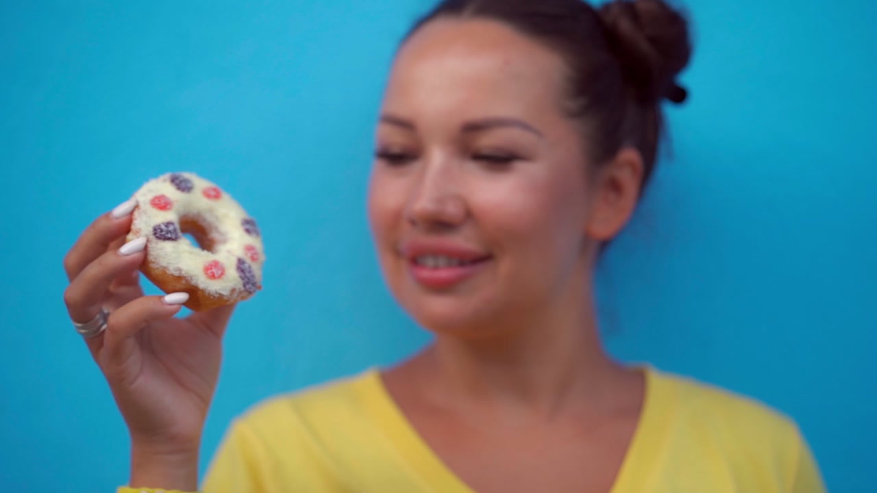 Young Woman Holding and Eating a Glazed Donut