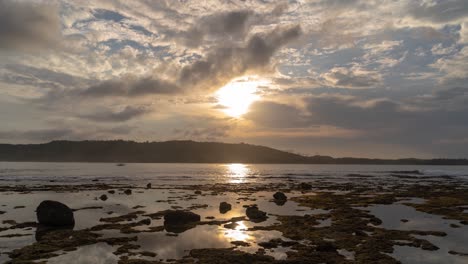 tropical coastal landscape with rocky shore and sun breaking through clouds