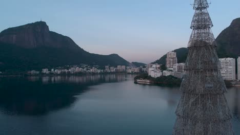 structure of the floating christmas tree on the city lake of rio de janeiro with the corcovado mountain and residential elite neighbourhood lagoa in the background at sunset