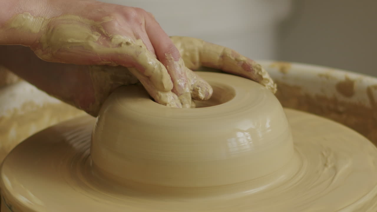 ручной крупный снимок толкания глины внутрь руками, чтобы сформировать отверстие для вазы