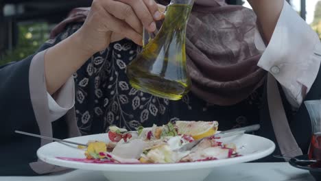 mujer vertiendo aceite de oliva en ensalada