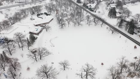 aerial, community suburb park covered in snow during winter, leafless treees