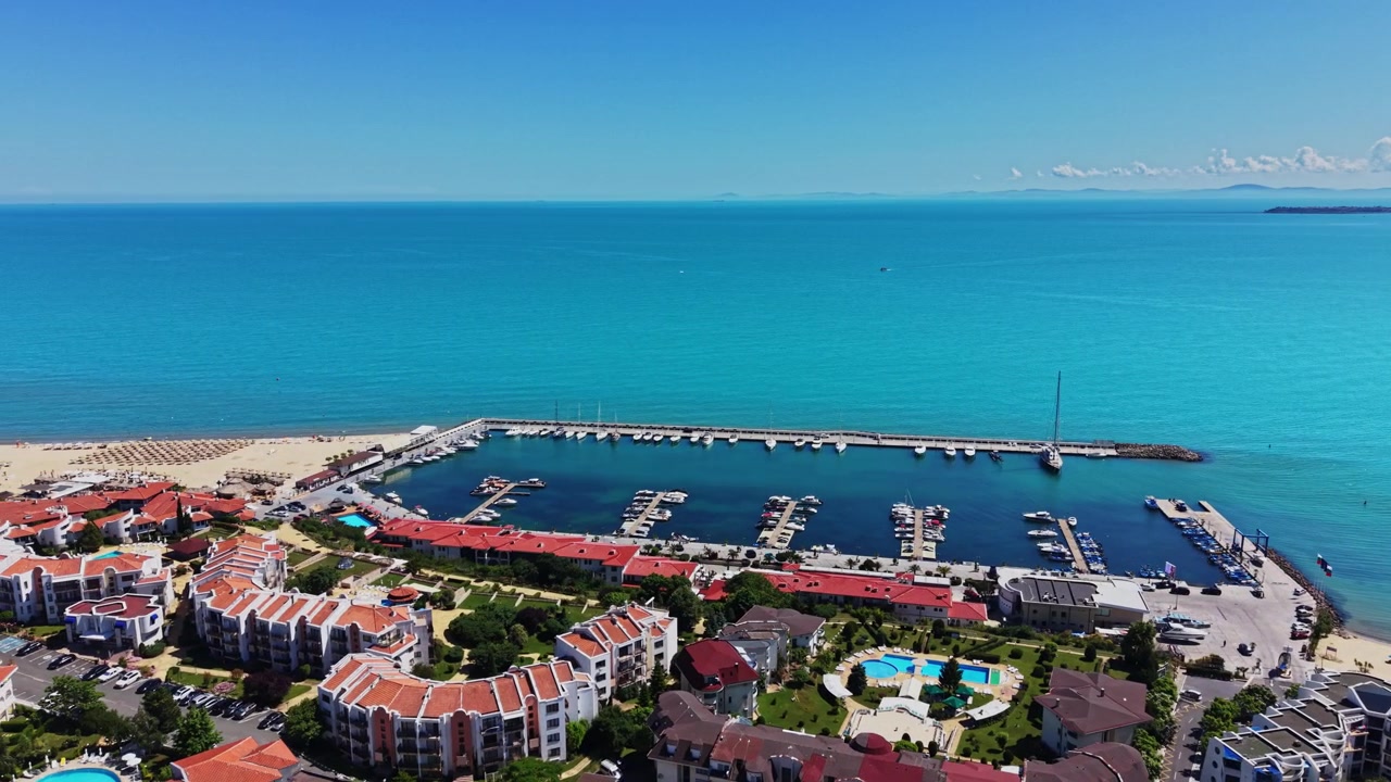 Bir kıyı marinasında berrak mavi su kumlu plajla buluşuyor.