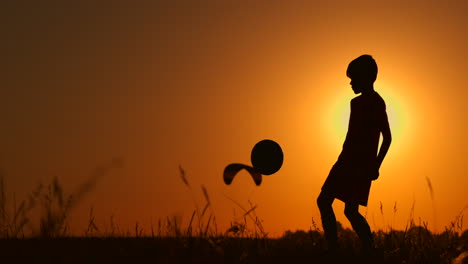 silhouette of a boy playing football or soccer at the beach with beautiful sunset background childhood serenity sport lifestyle concept.