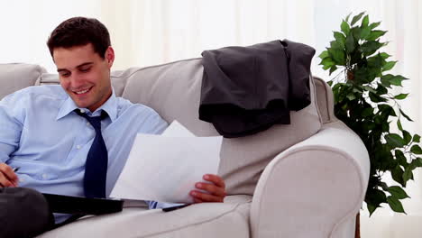 hombre de negocios sonriente sentado y trabajando en un sofá