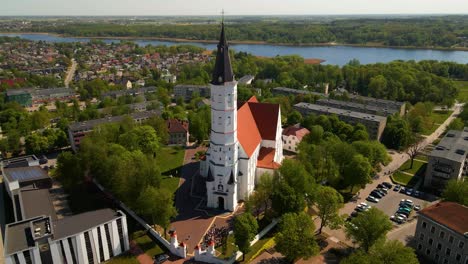 Aerial-shot-of-the-city-church-Siauliai,-Cathedral-of-Saints-Peter-and-Paul,-on-a-sunny-day-by-the-river-Siauliai,-Lithuania,-paralax-shot