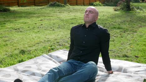 un hombre relajándose en un jardín practicando la atención plena con los ojos cerrados relajándose en una alfombra en la hierba afuera en la naturaleza