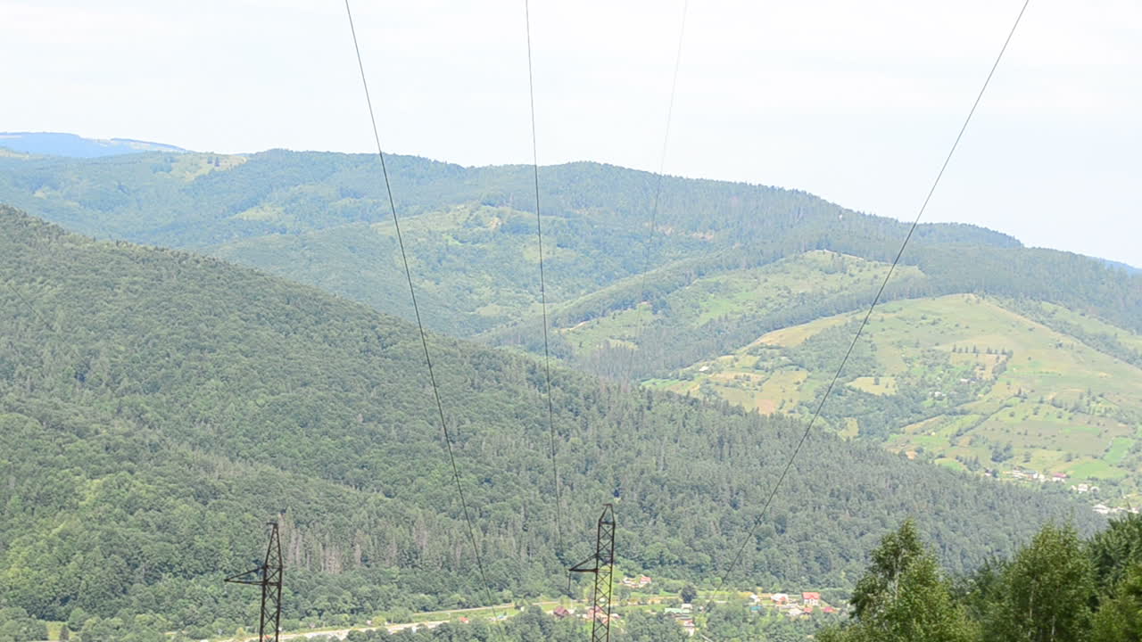 Elektrické vedení na pozadí hor. Sloupy a dráty