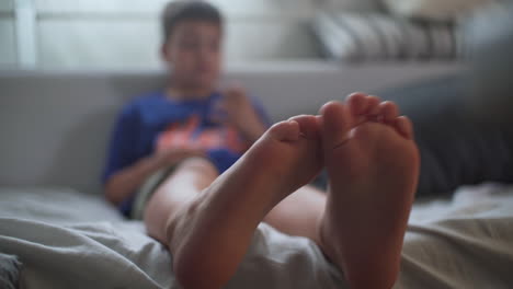 Close-up-isolated-shot-of-toddler's-feet,-with-blurry-background,-sitting-at-house's-sofa
