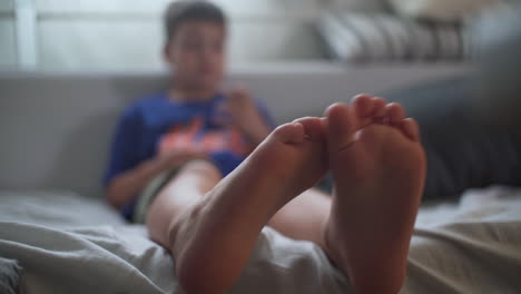 close up isolated shot of toddler's feet, with blurry background, sitting at house's sofa