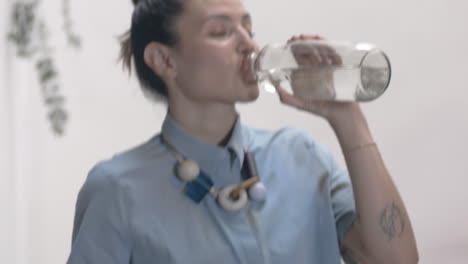 Hermosa-Mujer-Bailando-Con-Una-Botella-De-Agua-Dentro-De-Su-Casa,-Una-Botella-De-Vidrio-De-Agua,-Escaleras,-Concepto,-Arte