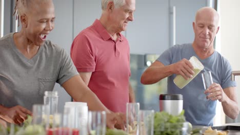 happy diverse senior friends preparing health drinks in kitchen, unaltered, in slow motion