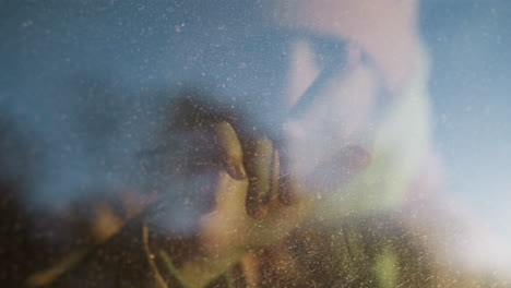 a young girl drawing with her finger on a foggy car window, creating a whimsical scene. her face is barely visible through the glass