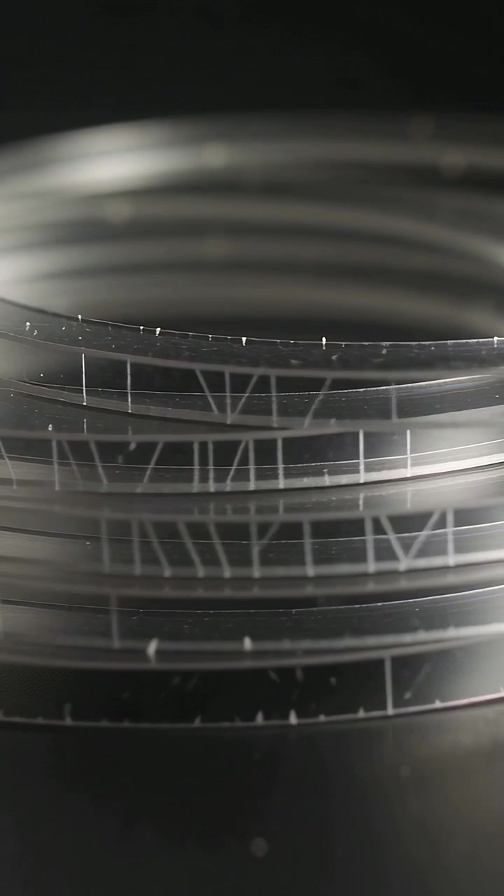Vertical video: Camera pulling focus over clear rings in studio revealing Roman numerals and dust