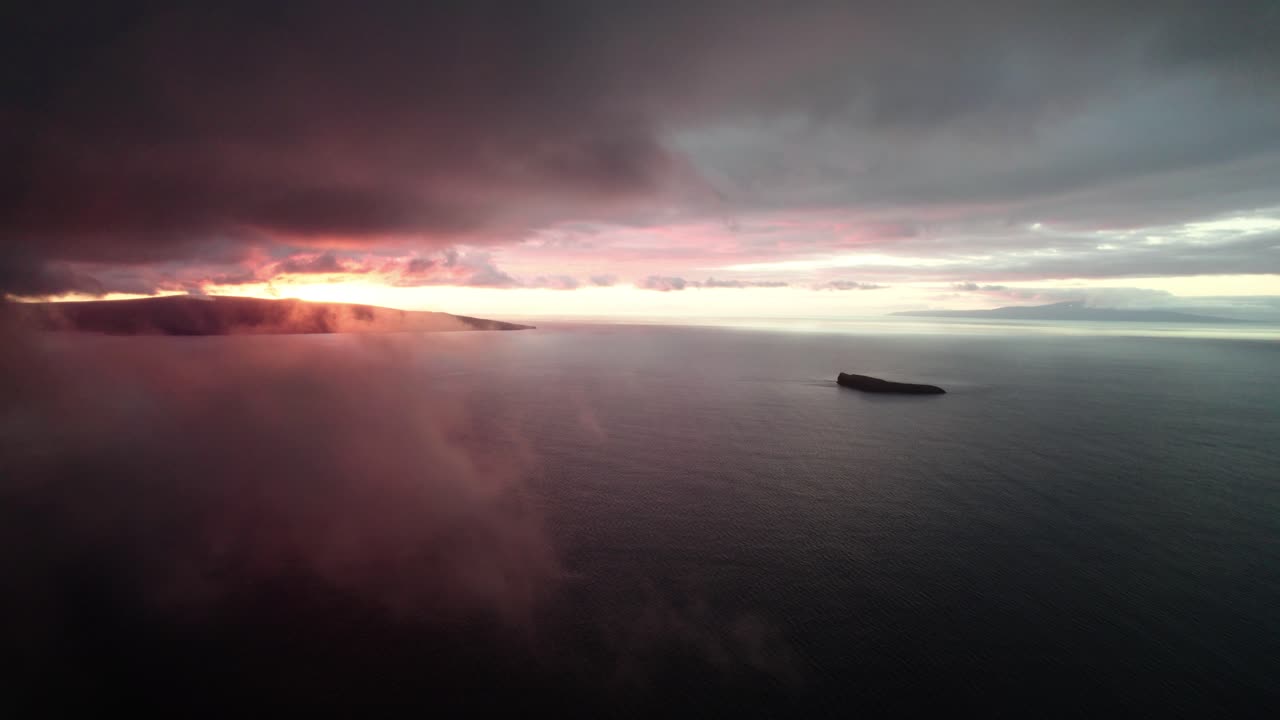 Incredibile ripresa aerea attraverso le nuvole sull'Oceano Pacifico con il cratere Molokini e l'isola sacra di Kaho'olawe in lontananza durante un incredibile tramonto colorato su Maui, Hawaii