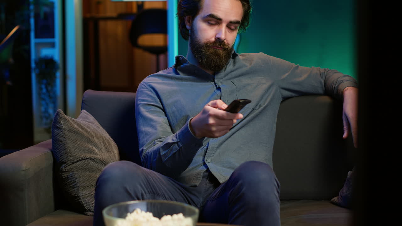 Mand på sofaen browser gennem film på streamingtjeneste ved hjælp af fjernbetjening