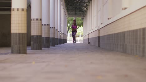 African-american-woman-wearing-earphones-running-in-the-corridor