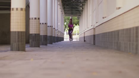 mujer afroamericana con auriculares corriendo en el corredor