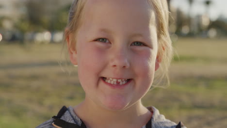 close up portrait beautiful little blonde girl smiling happy enjoying relaxed summer day on urban park at sunset slow motion